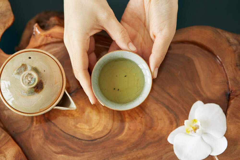 Xícara com chá branco em cima de mesa de madeira.