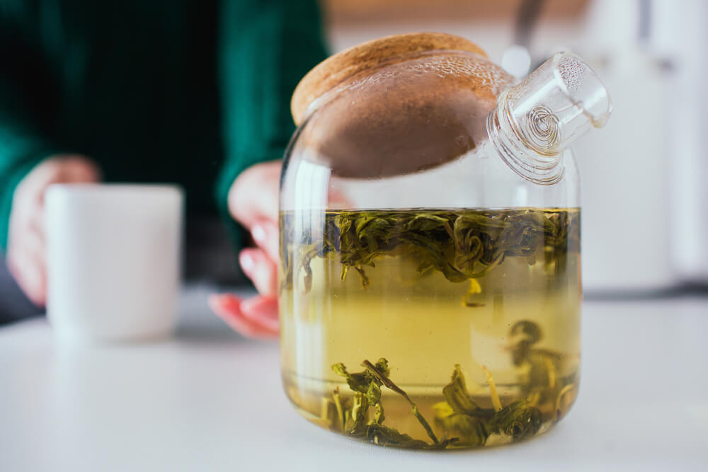 Bule de vidro com chá verde infusionando.